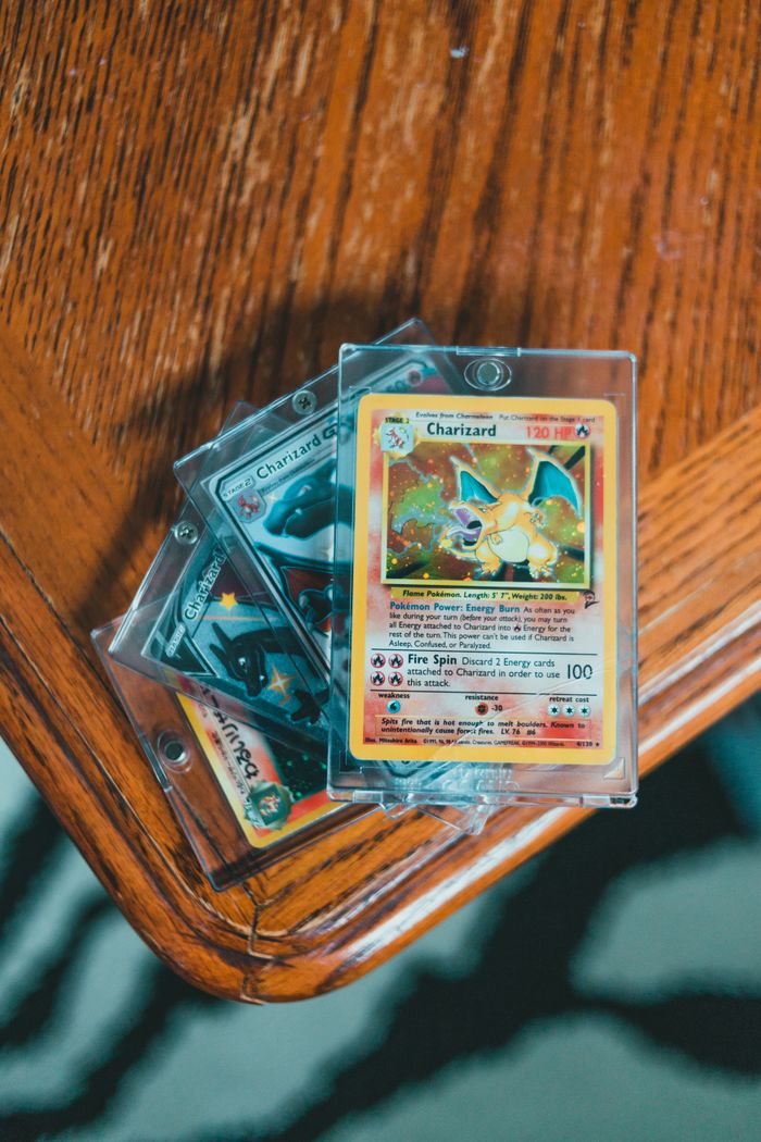 A set of valuable Pokemon trading cards displayed in protective cases on a wooden table.